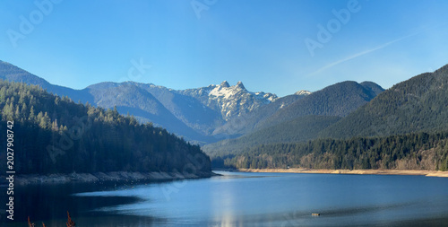 Cleveland Dam reservoir with The Lions peaks and forested mountains, Vancouver