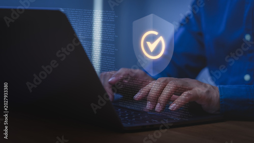 Hands typing on a laptop computer with a digital shield. Cybersecurity technology ensures data privacy, protection, and a secure internet network.