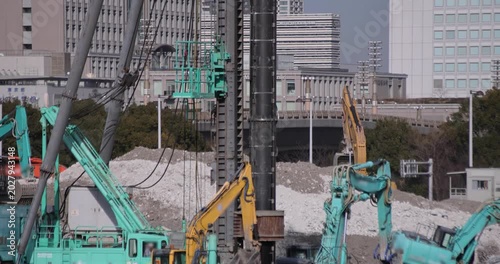 Moving cranes at the under construction in Tokyo in winter telephoto shot tilt up