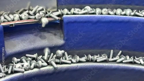 Vibratory boel feeder sorting screws on a conveyor belt for quality control inspection in an automated factory.	