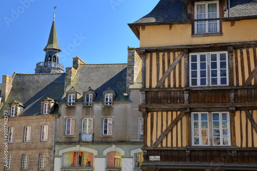 Traditional half-timbered medieval houses located along Place des Merciers (Merciers Square) in  Dinan, Brittany, Cotes d'Armor, France, with the Clock Tower in the background
