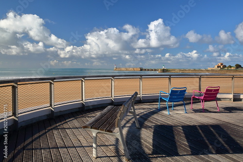 The beach in Les Sables d'Olonne, Vendee, France, viewed from the esplanade, with benches and colorful chairs in the foreground