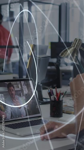 Vertical video: Arm moving lamp using mouse sparking light rays sweeping over laptop on office call