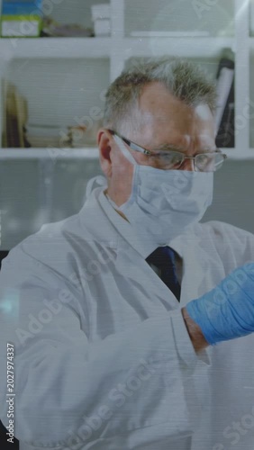 Vertical video: Lab tech lifting beaker, pipetting while inspecting yellow sample overlay appearing
