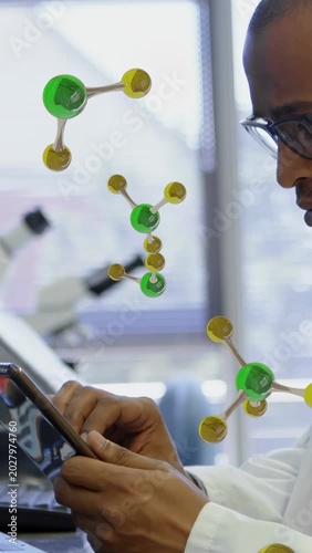 Vertical video: Lab scientist tapping tablet, causing molecules floating near face while studying