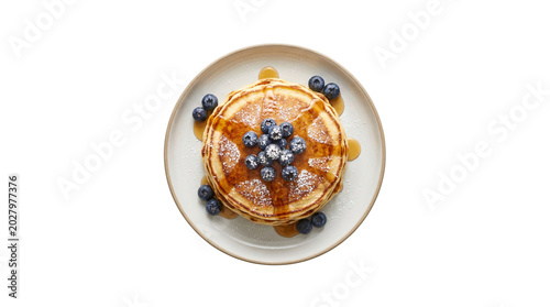 Overhead view of pancakes with blueberries and syrup.