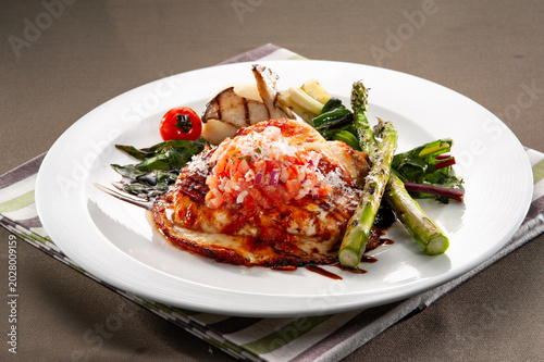 Foto Baked chicken breast parmigiana with melted mozzarella cheese and tomato sauce,
