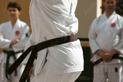 Photos A karateka in a white kimono with a black belt throws punches.
