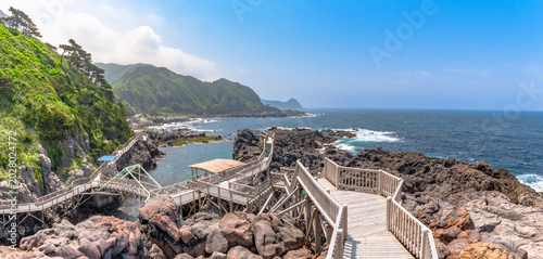 Scenic wooden boardwalk over crystal clear turquoise sea in Akasaki Promenade, Kozushima Island, Japan.