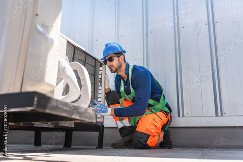 HVAC technician measuring refrigerant pressure in air conditioning system, Air conditioner maintenance, technician service checking outdoor refrigerant levels air conditioner unit in factory or home