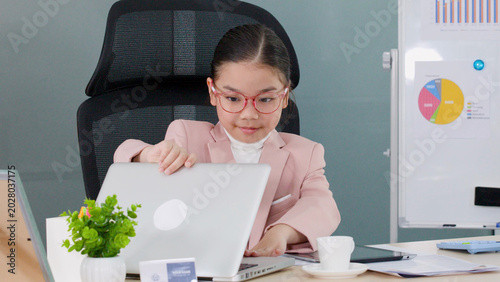 Canvas Print Young Asian girl in pink suit roleplaying as businesswoman at office desk