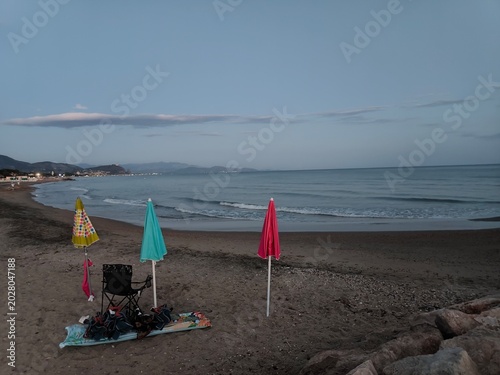 Obraz na plátne Mediterranean Beach Dusk Three Colorful Umbrellas Calm Sea Terracina Evening
