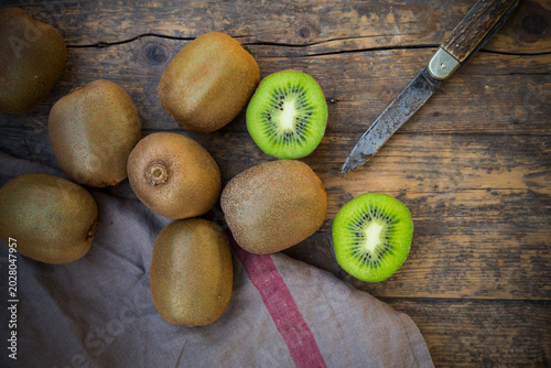 Kiwis (Actinidia deliciosa) and pocketknife on wooden table
