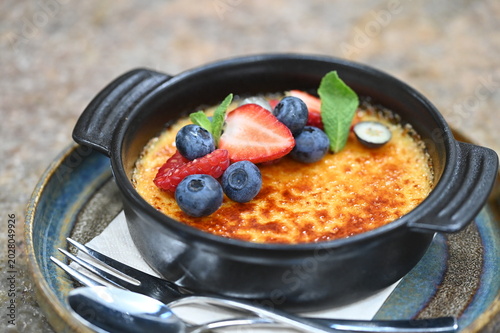 Photos French crème brûlée dessert with fresh fruit served in a black bowl