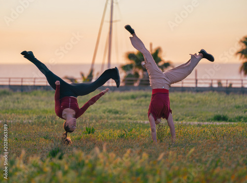 Photography Two athletic women performing impressive handstands and acrobatic flips in a gre