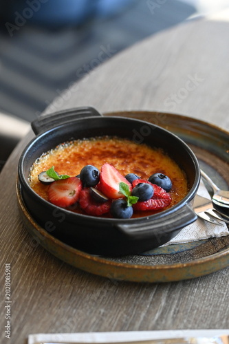 Obraz na plátně French crème brûlée dessert with fresh fruit served in a black bowl