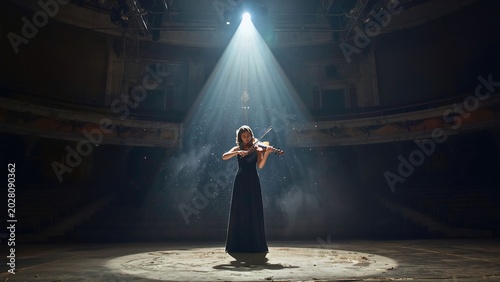 Female violinist performing alone inside abandoned theater illuminated by single spotlight, floating dust particles, dramatic cinematic shadows, realistic emotional expression