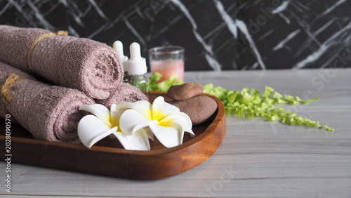 Photography Luxury spa still life with rolled towels, tropical flowers, massage stones and essential oil on wooden tray