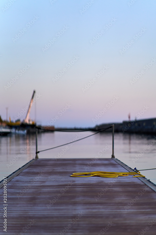 Fototapeta premium Empty wooden dock extending into serene twilight harbor
