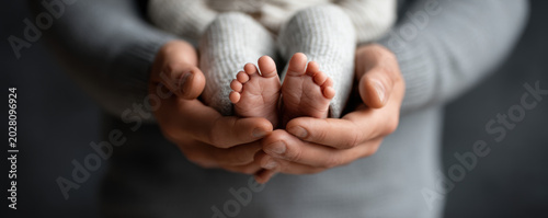 Father day dad daddy baby foot parent hand newborn infant family love care tenderness closeup of tiny feet held gently for father day celebrating