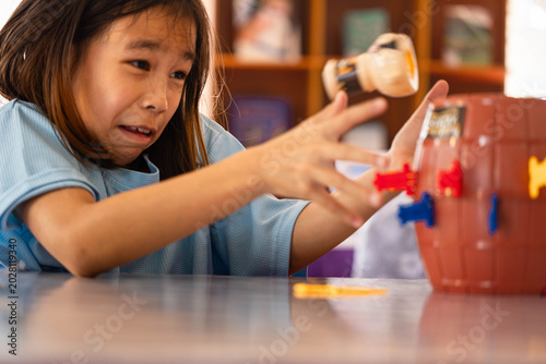 Photos Excited little girl flinching as the pirate pops up while playing a classic barrel board game at home