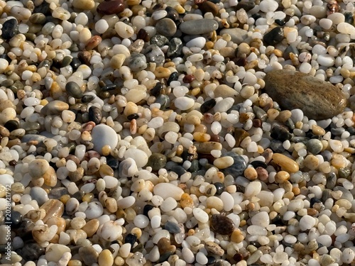 Schilderij op canvas Pebble beach close-up showing various colorful stones and textures, suitable for