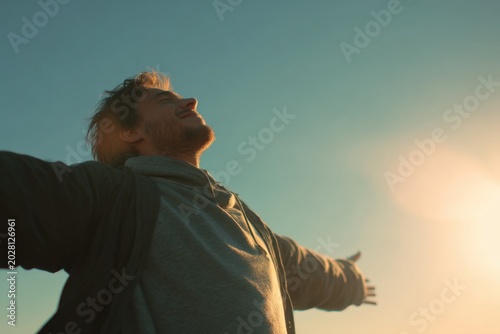Young man with arms open to sky, feeling freedom and happiness outdoors