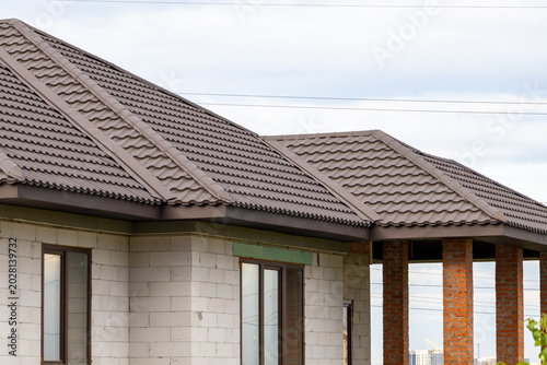 Принти на полотні Newly Constructed House With Sloped Brown Roof and Brick Features Under Cloudy S