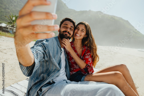 Couple on beach taking selfie during vacation
