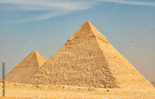 Pyramids stand tall under clear blue sky in Giza, Egypt during sunny afternoon with timeless legacy visible