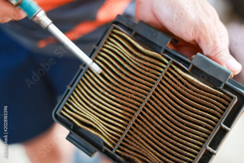 Foto Mechanic holding dirty automotive air filter blowing compressed air through meta