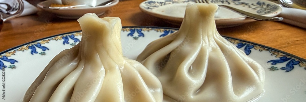 Εκτύπωση καμβά Steamed khinkali dumplings on decorative ceramic plate, rustic wooden table sett