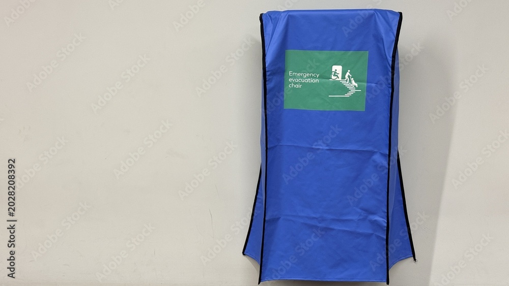 Εκτύπωση καμβά Blue emergency evacuation chair cover mounted on a wall, clean indoor corridor s