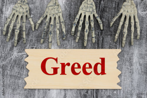 Billede på lærred Greed text with two pairs of skeleton hands on with a sign weathered wood