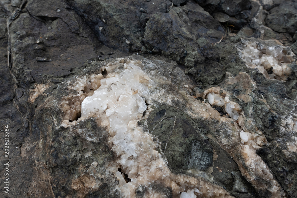 Fototapeta premium Close-up of a raw calcite mineral formation embedded within a dark rock matrix