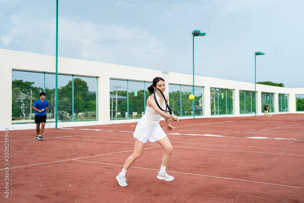 Obraz premium Asian sportsman and woman playing tennis match on outdoor clay court.