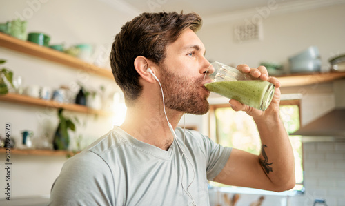 Foto Wellness, earphones and man in home with smoothie, organic juice and protein shake for gut health