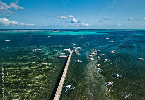 Aerial drone view of traditional outrigger boats scattered across the shallow reef flats of General Luna, Siargao Island, Philippines during low tide.