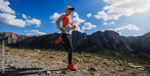 Trail runner running at high altitude grassland mountain top road