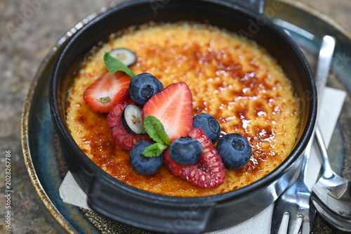 Obraz na plátně French crème brûlée dessert with fresh fruit served in a black bowl