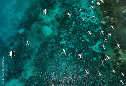 Foto Aerial drone view of traditional Filipino outrigger boats floating above vibrant coral reefs near Daco Island, Siargao, Philippines