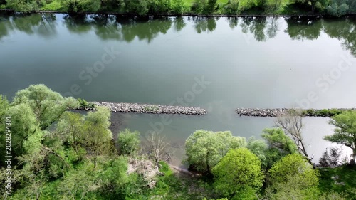 Drohne fliegt über Fluss mit Steinbuhnen und Auwald, Uferschutz, Luftaufnahme