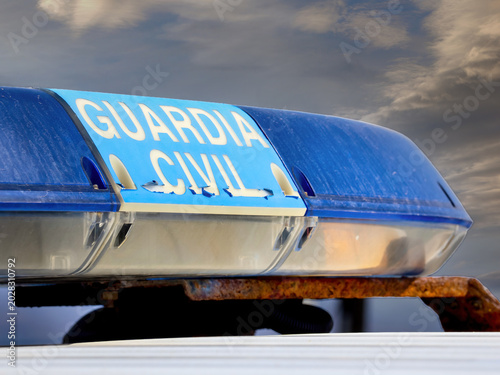 Blue police emergency light on patrol vehicle against dramatic cloudy sky, spanish Guardia Civil