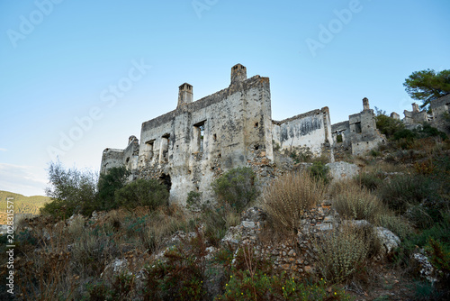 Large abandoned stone mansion sitting in ruins on a deserted village hillside