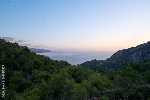 Twilight sunset view of a quiet ocean bay nestled between green mountain slopes