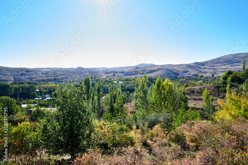 Wide scenic view of a green valley and distant mountains under a clear blue sky