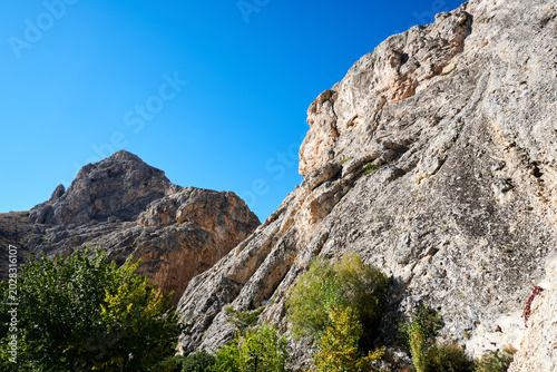 Dramatic steep rocky mountain cliff face towering under a clear blue sky
