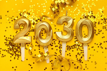 Golden 2030 candles with confetti on yellow background celebration concept