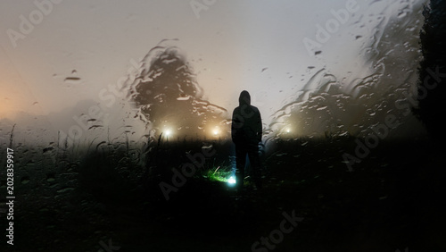 An eerie ghost like blurred, hooded figure standing in a spooky field at night
