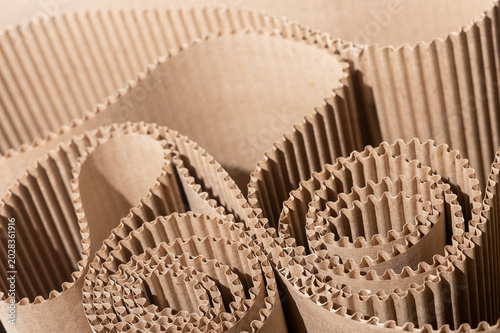 Rolled corrugated cardboard packaging in close up. Brown kraft paper texture with layered folds and ribbed surfaces. Sustainable shipping background for industrial design and